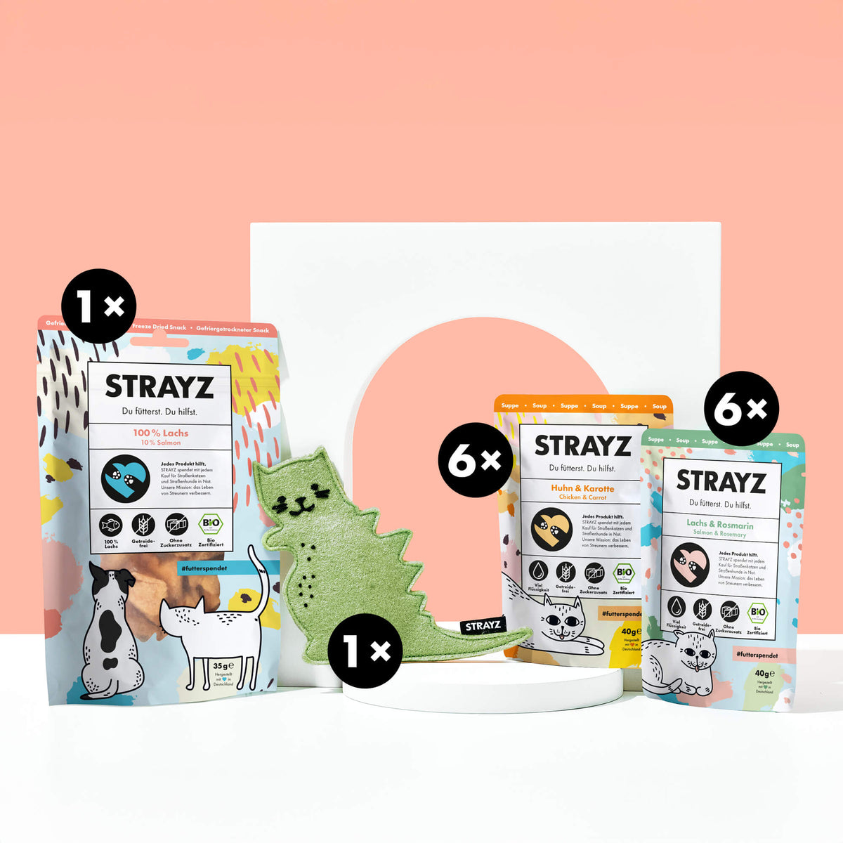 Geschenk für Katzen von STRAYZ. Das Paket besteht aus einem Baldirankissen mit dem Namen Catzilla. Das Katzenspielzeug ist wiederbefüllbar. Zudem sind natürliche Bio Katzenleckerli von STRAYZ enthalten. 6 Mal die Suppe Huhn & Karotte, 6 Mal die Katzensuppe Lachs & Rosmarin sowie 100 % Lachs. Gefriergetrocknetes Bio Lachsfilet für allergische Katzen.
