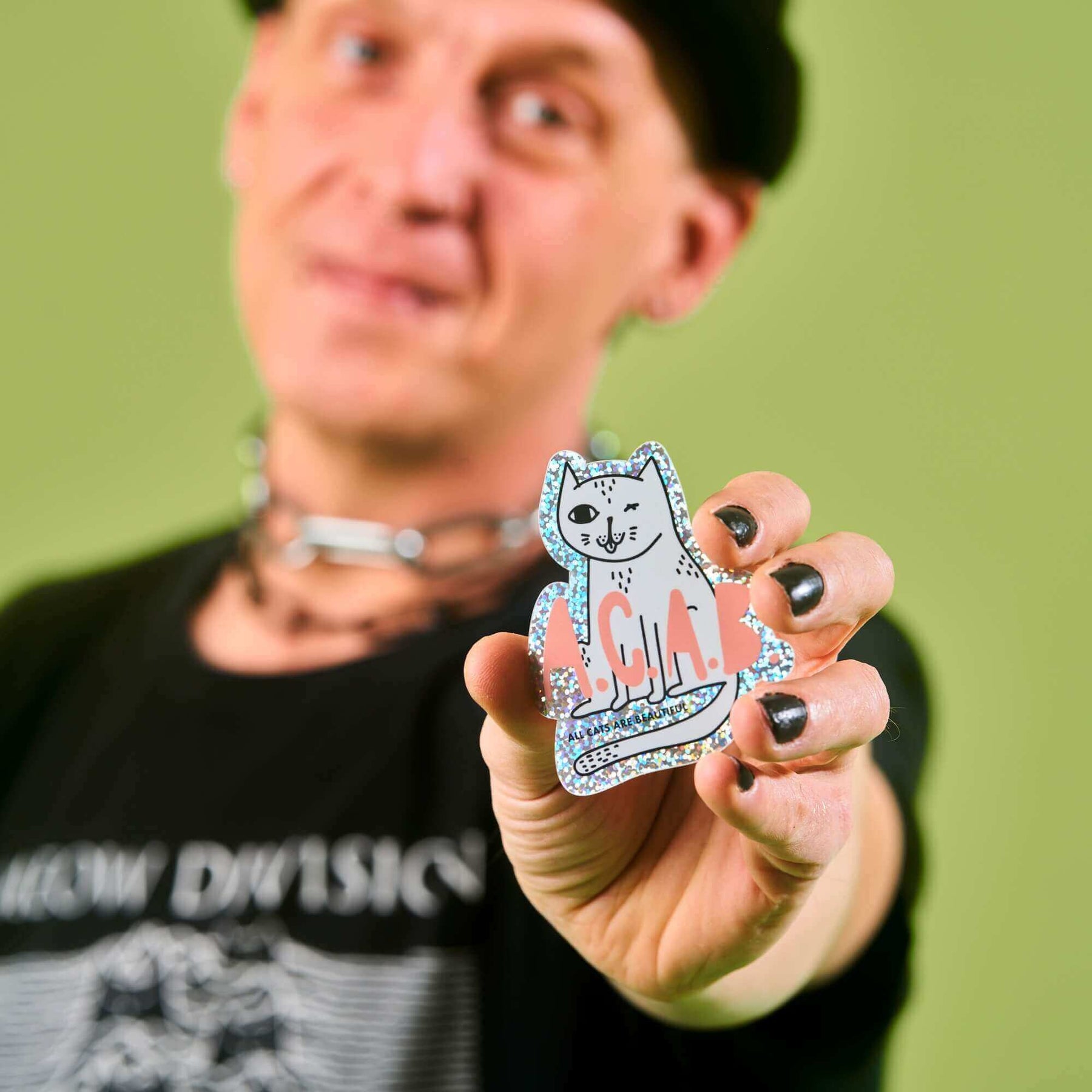 STRAYZ Katzen Glitzersticker ACAB "All Cats Are Beautiful" von einem Mann in die Kamera gehalten.