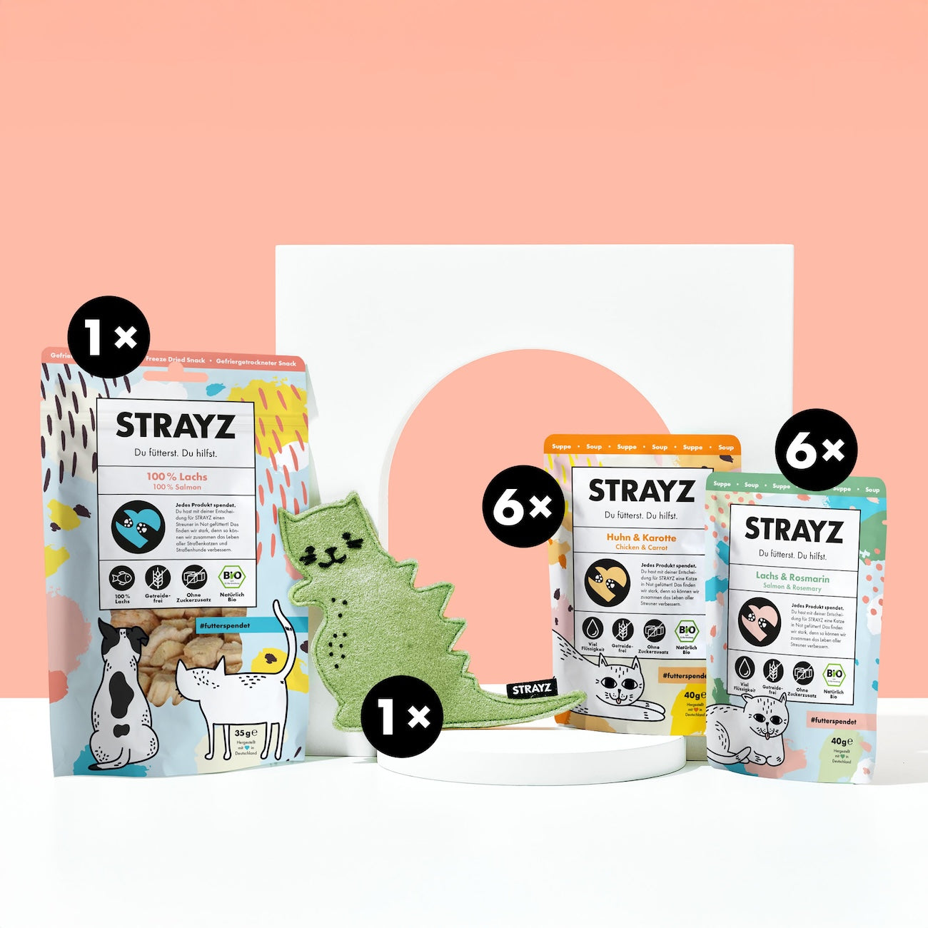 Geschenk für Katzen von STRAYZ. Das Paket besteht aus einem Baldirankissen mit dem Namen Catzilla. Das Katzenspielzeug ist wiederbefüllbar. Zudem sind natürliche Bio Katzenleckerli von STRAYZ enthalten. 6 Mal die Suppe Huhn & Karotte, 6 Mal die Katzensuppe Lachs & Rosmarin sowie 100 % Lachs. Gefriergetrocknetes Bio Lachsfilet für allergische Katzen. 